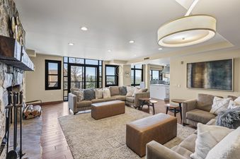 A spacious and elegantly furnished living room in Lowell 401 0, featuring comfortable sofas, a large area rug, a fireplace, and expansive windows showcasing a mountain view.