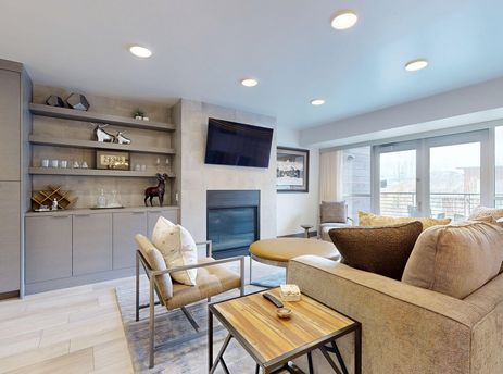 Modern and cozy living room with a fireplace and glass patio doors at Peak Retreat.
