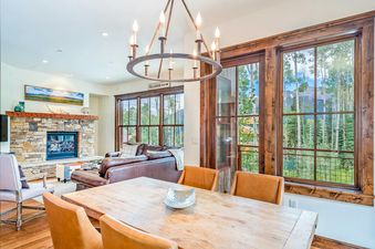 The dining area in Trails Edge 1 Mountain Village features large windows and a rustic wooden table.