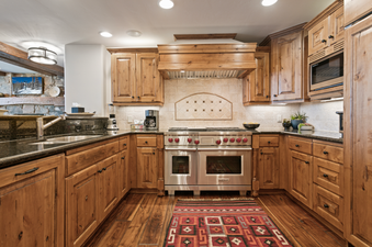 The kitchen in Grand Lodge Three Bedroom Deluxe 408 features stainless steel appliances, wooden cabinetry, and granite countertops.