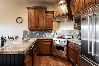 A gourmet kitchen with dark wood cabinets, granite countertops, and stainless steel appliances at 103 Juniper Landing.