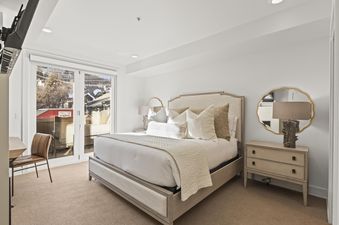 A serene bedroom at Rio Grande 203 with a large bed, stylish nightstands, and a glass door leading to an exterior view.