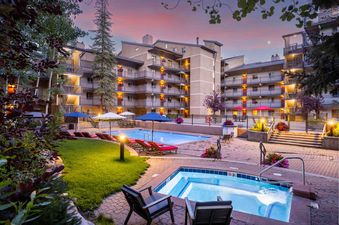 An inviting outdoor pool and hot tub area at Vantage Point 501, beautifully illuminated at twilight with comfortable lounge chairs and lush greenery.