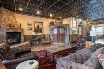 A cozy living room features leather chairs and a stone fireplace.