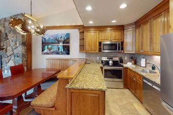 The kitchen in Manor Vail 339 features stainless steel appliances, granite countertops, and a dining table.