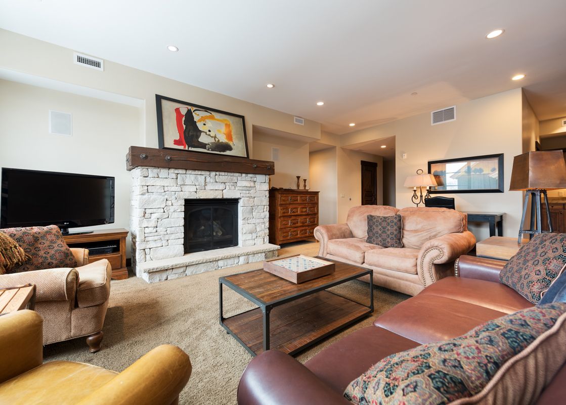 The comfortable and elegantly furnished living area at Silver Star 4202, showcasing a stone fireplace, plush seating, and a flat-screen television.