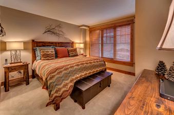 A bedroom with a king-sized bed, a wooden headboard, and a wooden chest at the foot of the bed.