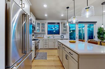 A modern kitchen at Blackstone 105 with stainless steel appliances, light cabinetry, a large island with white countertops, and contemporary lighting.