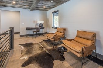 A cozy lounge and workspace landing at Headwaters Hideout with leather armchairs and a writing desk.