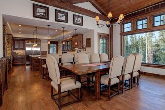 Enjoy dinner with friends and family around the beautiful dining table in Moonlight Basin 20 Peaks View, which features a view of the trees and mountains. The table features a rustic wooden finish.