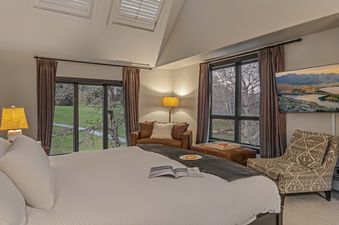 The bedroom in the Aspen Glade Retreat offers a luxurious king-sized bed, comfortable seating, and large windows with views of the natural landscape.