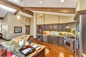 A spacious, modern kitchen with rich wooden floors, sleek stainless steel appliances, and a large kitchen island with bar stools.