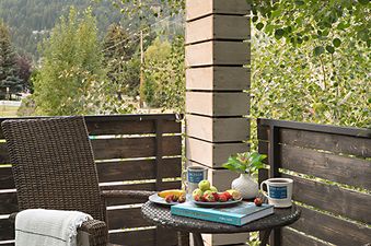 A cozy private balcony at Taminah Retreat with wicker rocking chairs, a small table with coffee and fruit, and mountain views.