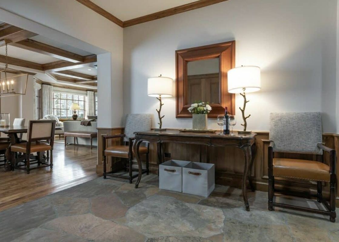 A welcoming foyer in Chateau Beaver Creek Residence 1403 with a console table, mirror, and seating, leading into a dining area with a long table and chairs.