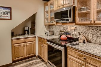 The kitchen at Breck Lodge features light wood cabinetry, granite countertops, and stainless steel appliances.