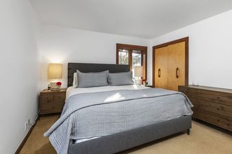 A cozy bedroom with a large king bed, warm wooden furnishings, and a window looking outside at Sundance Jackson Hole.