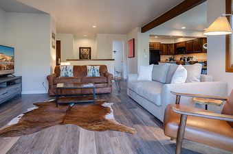 A comfortable living room in the Ranch at Steamboat RA605 with a leather sofa, flat-screen TV, and open-concept kitchen.
