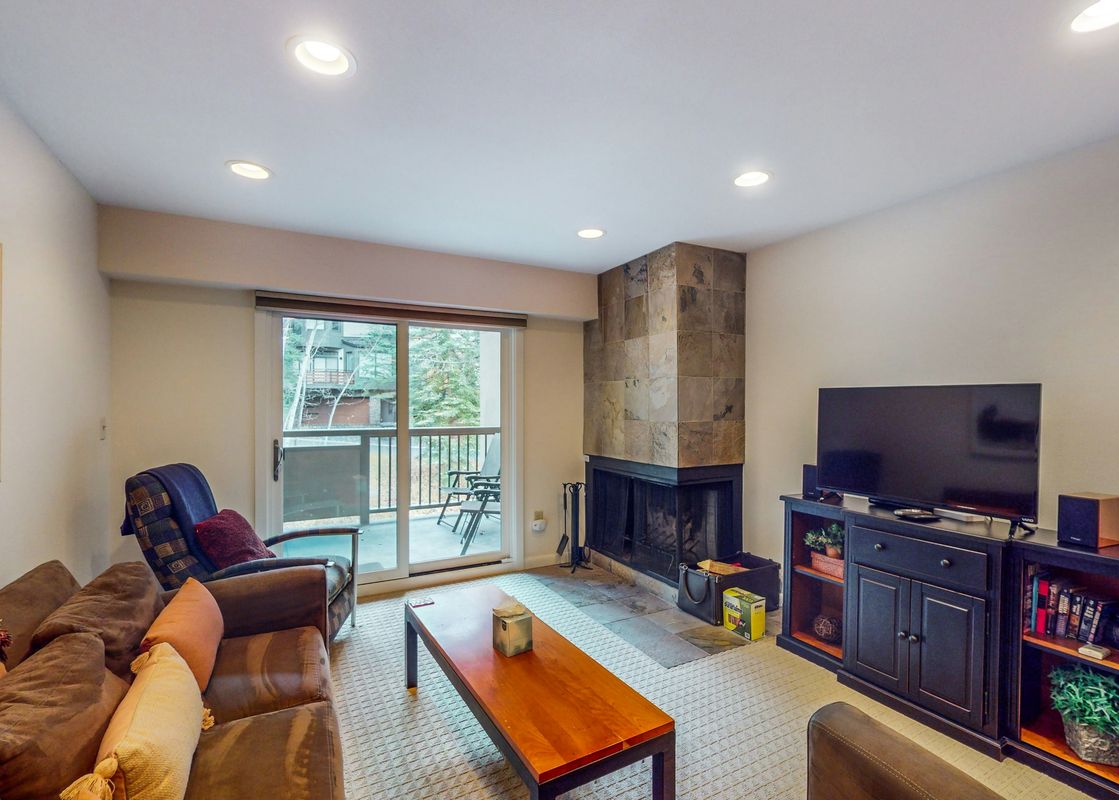 The living room of Fallridge 302, featuring a fireplace, a large couch, two chairs, and a coffee table.