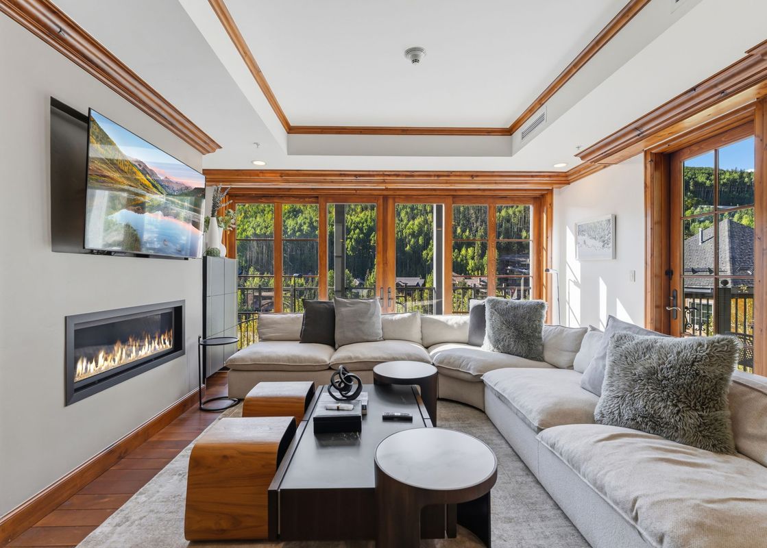 Cozy living room featuring a large sectional sofa, fireplace, and scenic forest views at Alpine at the Ritz Carlton.