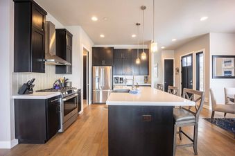 The kitchen in Frostwood Villa 4302 has stainless steel appliances, dark cabinets, and a white quartz island.
