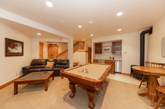 The Timber Trail Lodge features a well-lit recreation area with a pool table, comfortable seating, and a convenient wet bar, perfect for unwinding after a day of adventures.