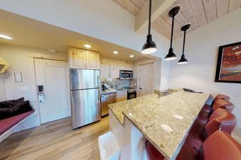 The kitchen in Manor Vail 364 has stainless steel appliances, granite countertops, and a breakfast bar with seating for four.