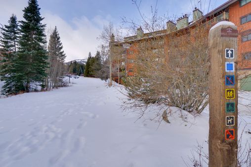 A snowy path leading to a ski-in ski-out condo complex in the mountains.
