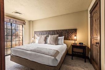 A cozy bedroom with a large bed, decorative headboard, and a window offering a view of the outdoors.