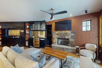 Living room in Settlers Lodge 104 with a large sectional sofa, fireplace, and large windows. The room features an abundance of natural light.