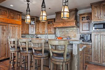 The spacious kitchen at the Retreat at Empire Pass features a large island with bar seating and custom wooden cabinetry.