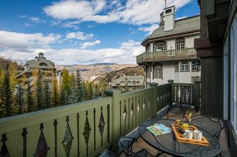 A private balcony at Chateau Beaver Creek Residence 406 with a patio table and chairs, offering scenic views of the resort buildings and autumnal mountains.