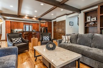 A spacious open-concept living room and kitchen in Cedar Crest Owl Cottage 9, featuring a grey sofa, wooden furniture, and recessed lighting.