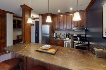 A view of the kitchen in Manor Vail 280, featuring stainless steel appliances and a granite countertop.