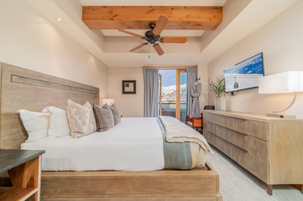 King-sized bed with plush bedding, a dresser, and a large television, all in a spacious and modern bedroom in Lumiere Two Bedroom Penthouse.