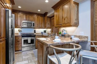 The kitchen at Abode at Dawn Patrol features wood cabinetry, granite countertops, and stainless steel appliances.