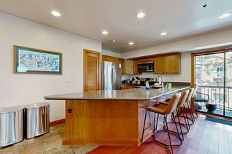 The kitchen at Silver Cliff Village 205 features a spacious breakfast bar with seating, a large refrigerator, and ample cabinetry, offering a bright and functional space.