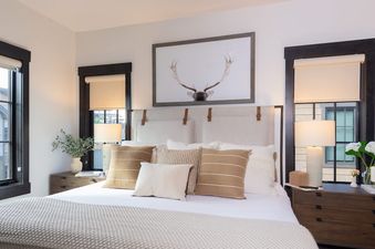 The primary bedroom at Rocky Mountain Retreat Winter Park features a bed with a white comforter, throw pillows, and two bedside tables.