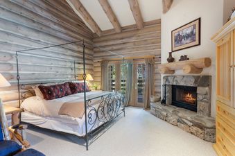 Pine Inn 3's master bedroom features a king size bed with a fireplace in the corner, a large window with a view of the woods, and a private bathroom with a jacuzzi tub.