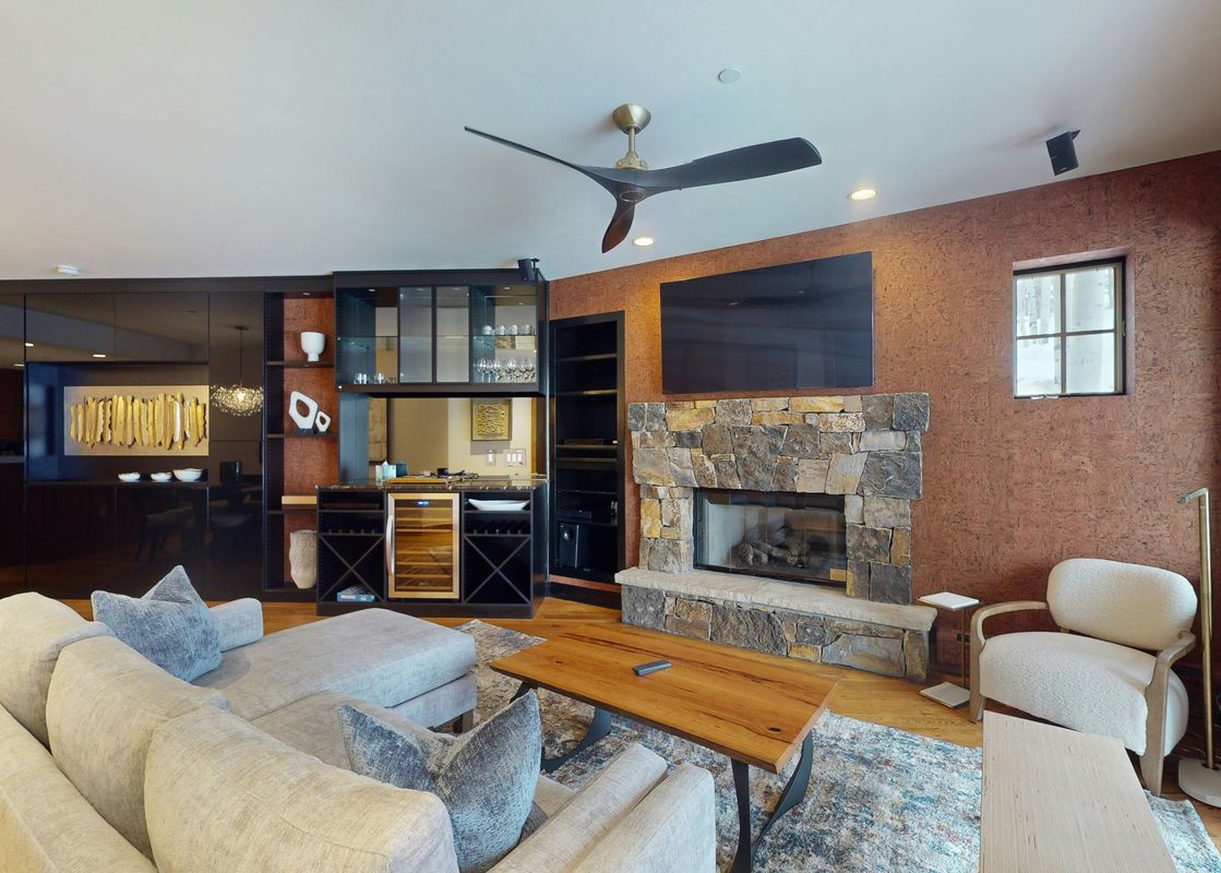 Living room in Settlers Lodge 104 with a large sectional sofa, fireplace, and large windows. The room features an abundance of natural light.