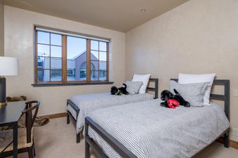 Two twin beds with black metal frames and striped bedding in a bedroom with a large window.
