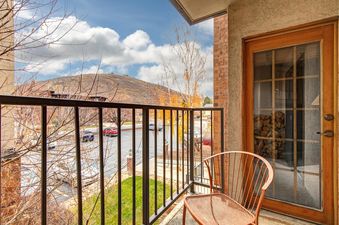 A private balcony at Copperbottom 207 features a chair and offers scenic views of mountains, trees, and a parking lot.