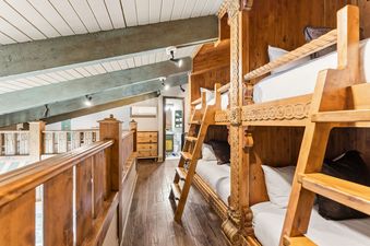 Cozy loft bunkroom featuring custom-built wooden bunk beds and rustic ceiling beams at Black Forest Dreams.