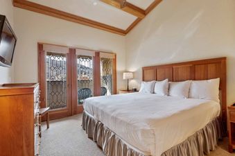 A king bedroom at The Charter F3205 with a large bed, wooden furniture, and glass doors leading to a balcony with mountain views.