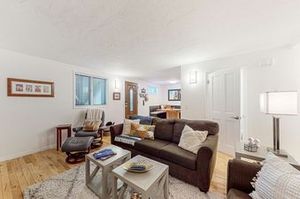 The living room at Emerald Pines at Motherlode C features a brown couch with pillows, two end tables, and a large rug.