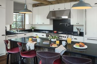 A modern kitchen with white cabinets, black countertops, and a large island set for breakfast.