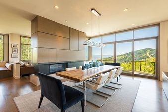 Modern dining area in Park City Colony Obsidian Ridge with a wooden table, fireplace, and scenic mountain views.