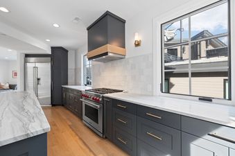 Modern kitchen with charcoal cabinets, white marble countertops, and a Wolf range.