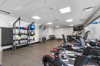 An indoor fitness center with a variety of equipment, including treadmills, ellipticals, stationary bikes, free weights, and a cable machine.
