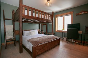 A cozy bedroom at Teewinot B4 featuring a custom wood bunk bed, a small desk with an office chair, and soft green walls.