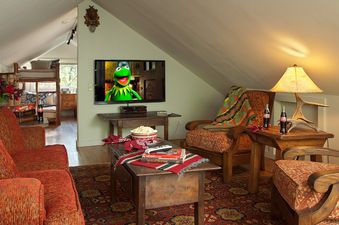 Cozy attic lounge with rustic furnishings, red sofas, and a TV at The Cabin in Jackson Hole.